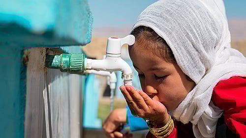 En flicka får rent vatten från en nyinstallerad vattenkran.