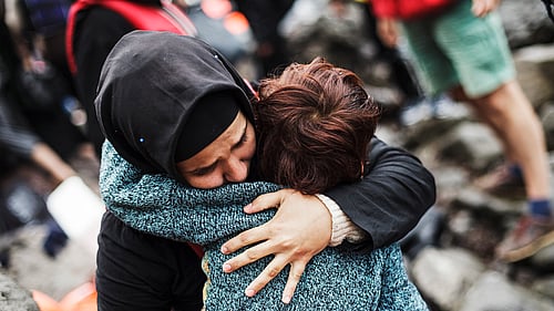 En syrisk flykting som korstat Egeiska havet från Turkiet i en ranglig båt kramar sin son efter att ha nått trygghet på ön Lesbos i Grekland.