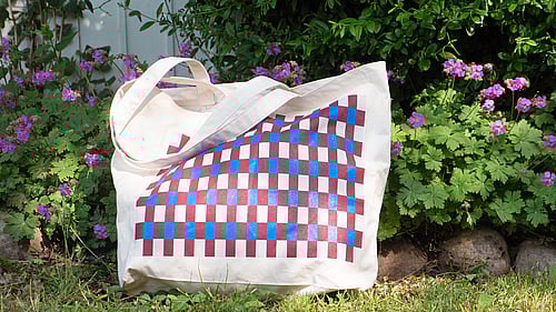 En tygkasse med rutigt mönster som är välkomstgåva för nya månadsgivare.