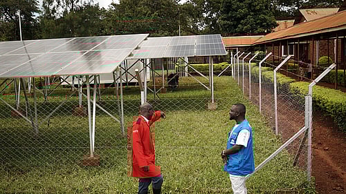 Två män samtalar framför solpaneler i Tanzania.