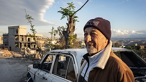 Mohammed, 80 år, står bredvid en krigsskadad bil i Tyros i södra Libanon. Mohammed flydde för sitt liv i september 2024, när en israelisk missil slog ner bara några meter från hans hem.