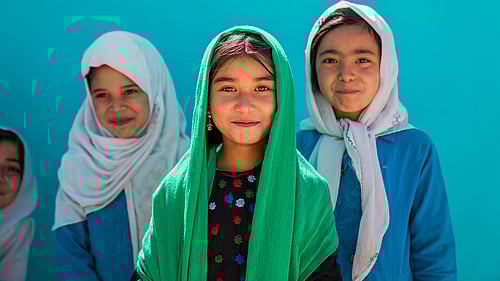 Tre flickor tittar in i kameran.