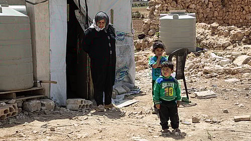 En kvinna och två barn står utanför ett tält.