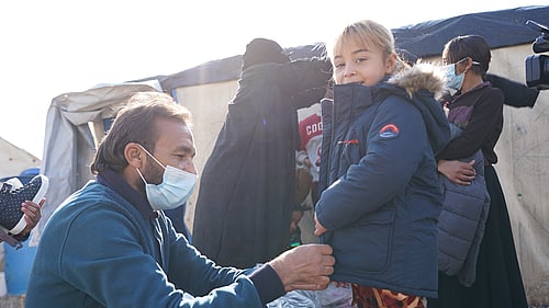 En man hjälper ett barn med en vinterjacka.