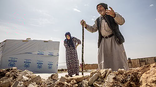 En äldre man och kvinna står utanför ett tält i Syrien.