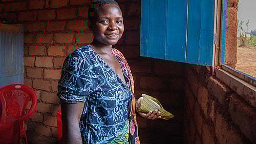 En kvinna står framför ett fönster. Hon ler mot kameran.