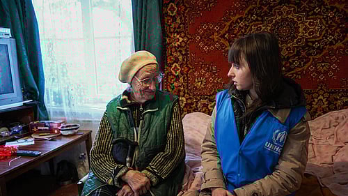 En äldre kvinna och en UNHCR-medarbetare sitter intill varandra.