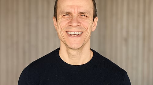 En man tittar in i kameran och ler.