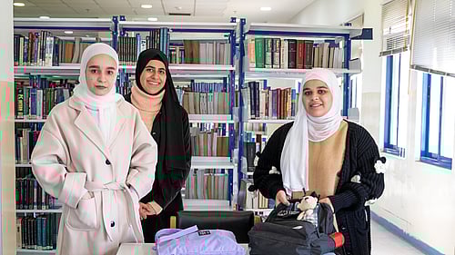 Tre kvinnliga studenter ler mot kameran.