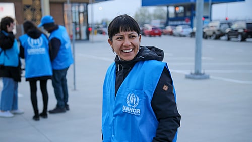 En kvinna med UNHCR-väst tittar in i kameran.