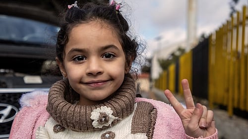 En flicka tittar in i kameran och gör fredstecken.