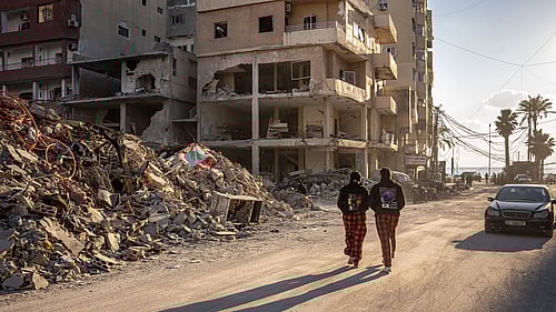 Människor på flykt mellan raserade hus.