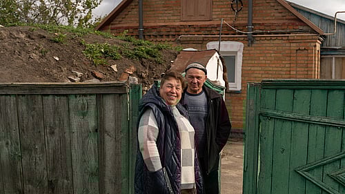 Ett ukrainskt par står framför en grön grind.