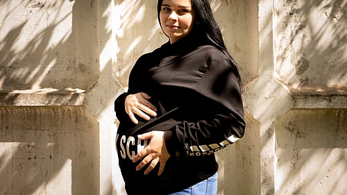 En gravid ukrainsk kvinna tittar mot kameran och håller sig varsamt om magen.