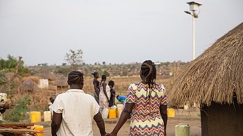 Två flyktingar går hand i hand, iväg från kameran.