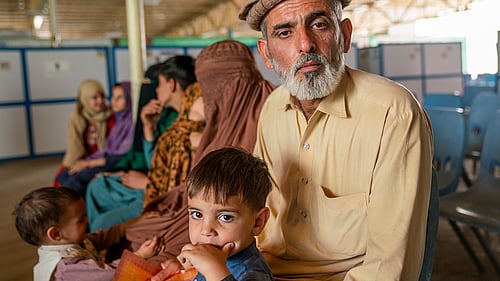 En afghansk man och hans son sitter på en bänk i ett mottagningscenter.