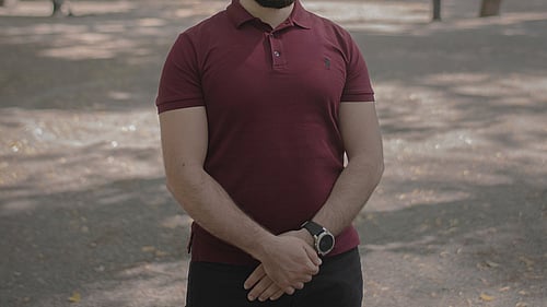 En man i mörkröd tröja står på en grusväg.