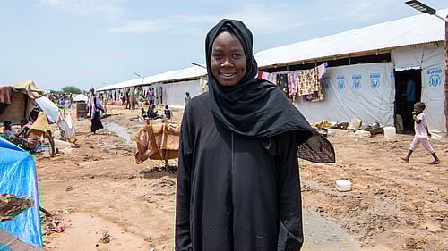 En kvinna står framför sitt RHU - Refugee Housing Unit.