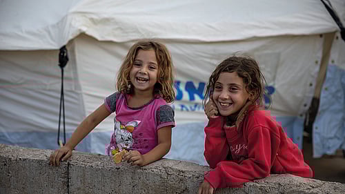 Två flickor står utanför deras UNHCR-tält i Irak.