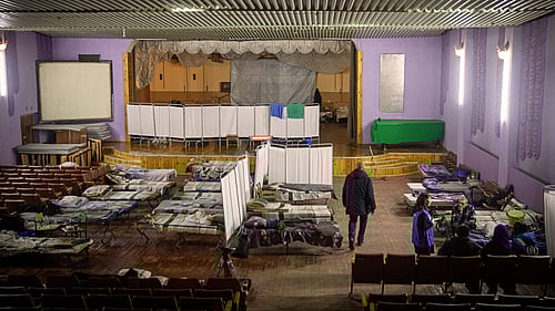 En bild som visar en sovsal i ett mottagningscenter. Sängar står på rad.