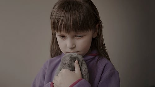 En liten flicka håller en kanin i famnen.