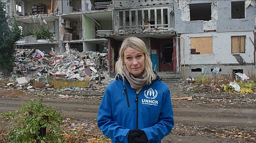 En kvinna tittar in i kameran. Hon har UNHCR-väst på sig.