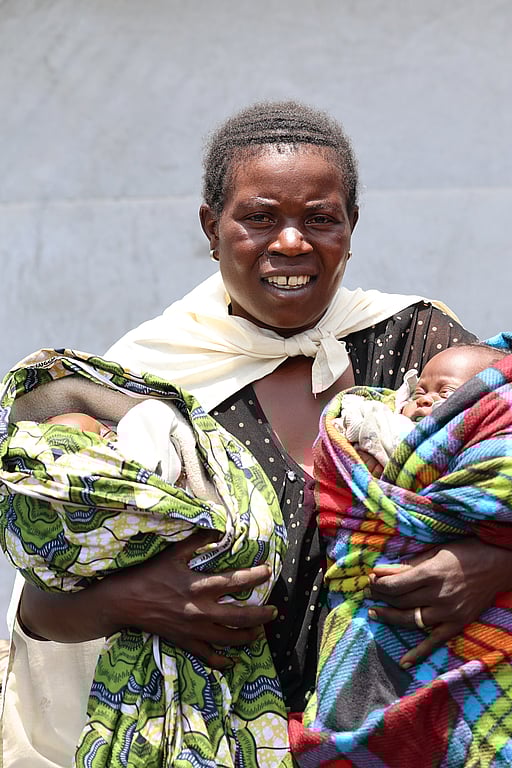 En kvinna håller två spädbarn i sina armar.