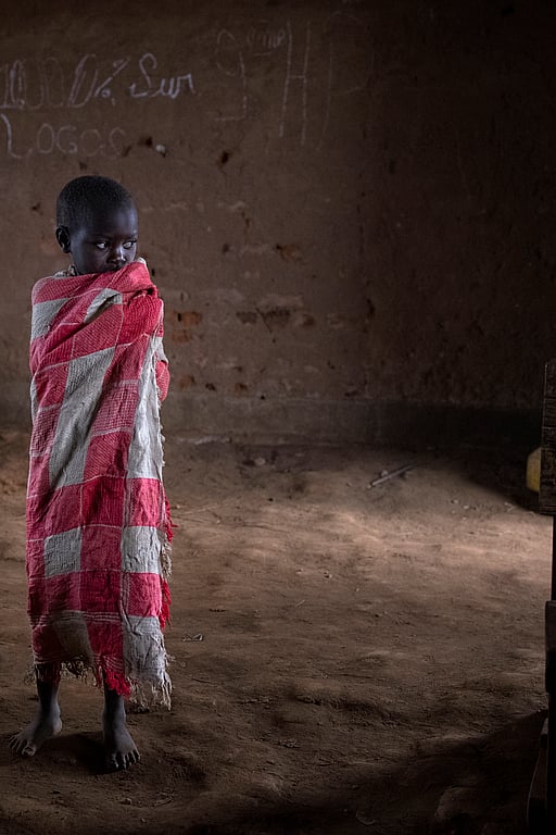 Ett litet skolbarn står ensam i ett klassrum i Kongo.