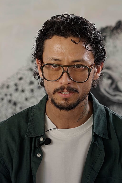 Ett foto på Hadi, som sitter framför en vägg.