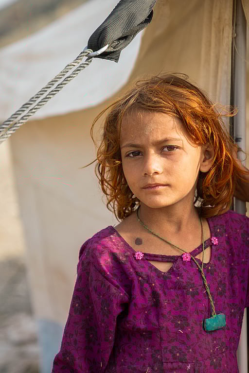 En flicka på flykt återvänder hem från Pakistan till Afghanistan. Här står hon utanför ett UNHCR-tält i Afghanistan nära gränsen till Pakistan.