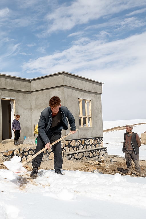 En familj röjer snö framför sitt nya hus i en bergsby i Afghanistan.