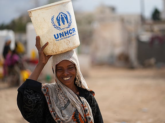 En kvinna på flykt i Jemen bär nödhjälp från UNHCR. Foto: UNHCR/Dotnotion