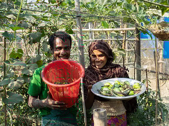 En man och en kvinna visar upp sina odlade grönsaker för fotografen.