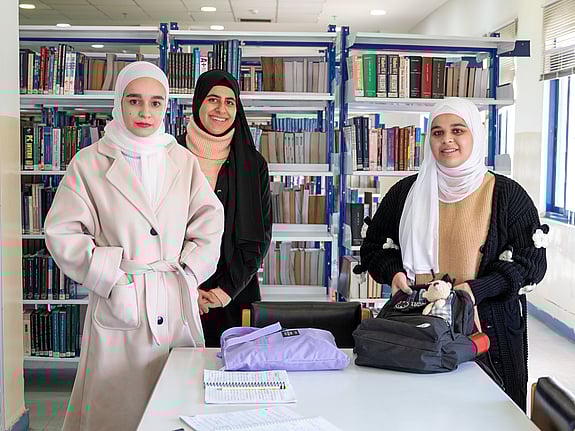 Tre kvinnliga studenter i Jordanien ler mot kameran.