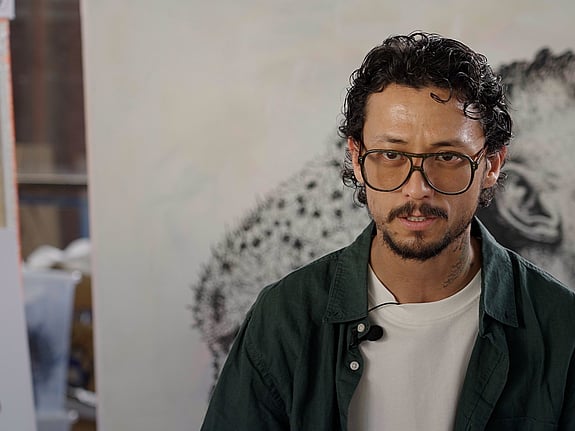 Ett foto på Hadi, som sitter framför en vägg.