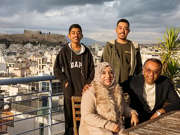 En familj som återförenats sitter tillsammans på ett tak i Aten.