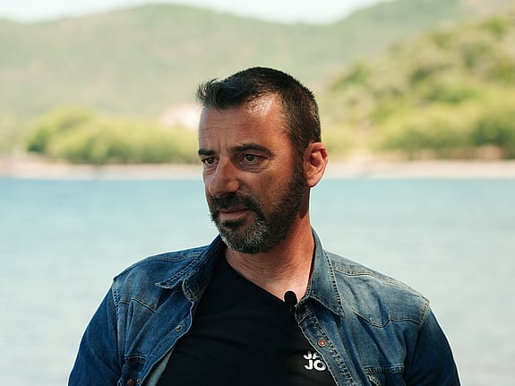 En fiskare står framför vattnet och intervjuas av en journalist.