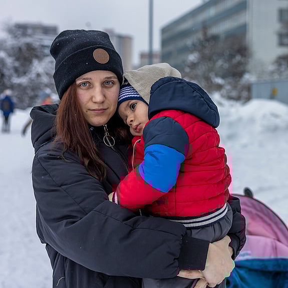 En ukrainsk kvinna och hennes barn står utomhus i snön.