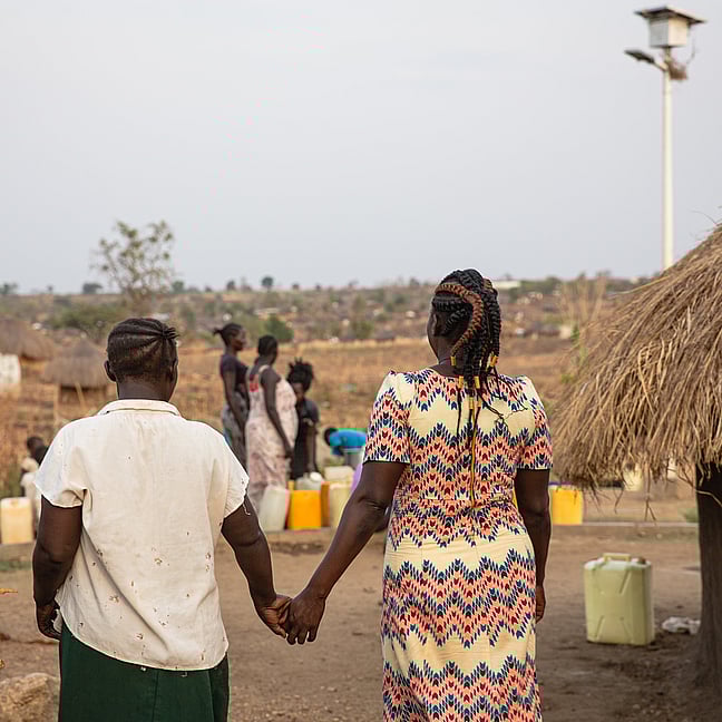 Två personer håller hand. De är på väg bort från kameran.