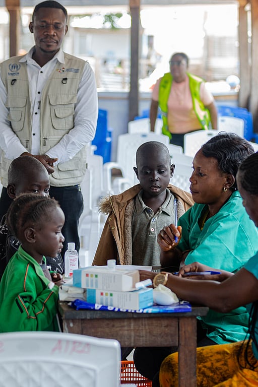 En familj sitter runt ett bord, tillsammans med UNHCR-medarbetare.