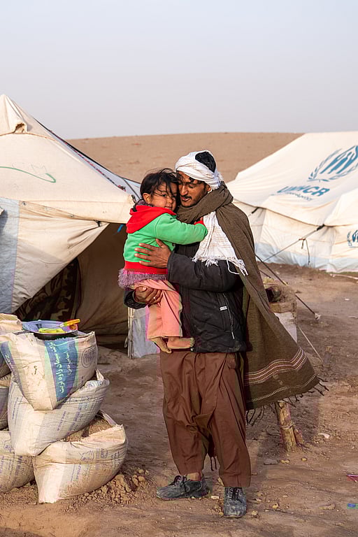 En pappa håller sitt barn i famnen när de står utanför sitt tält efter en förödande jordbävning i Afghanistan.