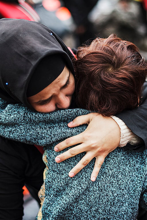 En syrisk flykting som korstat Egeiska havet från Turkiet i en ranglig båt kramar sin son efter att ha nått trygghet på ön Lesbos i Grekland.