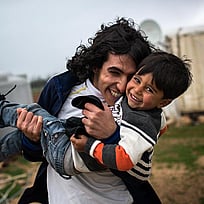 Två bröder kramar varandra och håller fram en mobiltelefon.