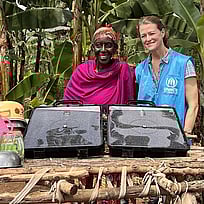 Två kvinnor står framför en solvatten-dunk och ler.