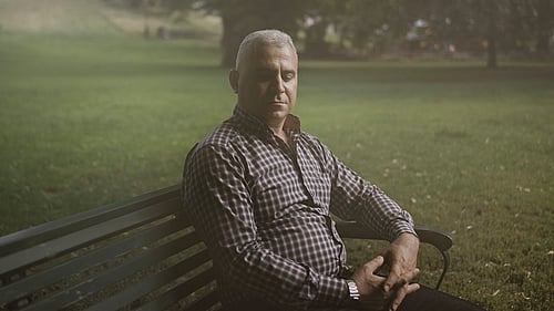 En man sitter på en parkbänk.