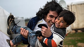 Två bröder kramar varandra och håller fram en mobiltelefon.