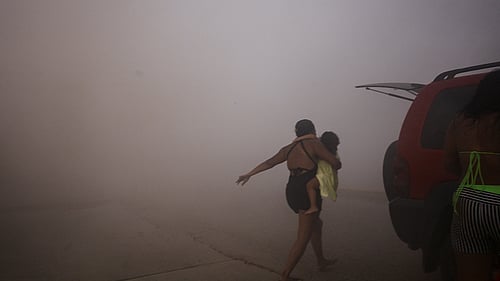 Jordbävning i Venezuela. A woman runs with a kid to take cover during an earthquake, in La Guaira, Venezuela, June 24, 2026. Foto: REUTERS/Maxwell Briceno