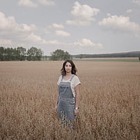 En kvinna står på ett fält med högt gräs.