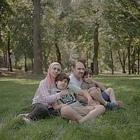 En familj på flykt från Syrien sitter i gräset.