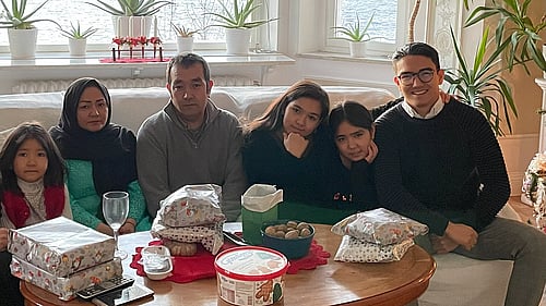 En familj sitter i en soffa, framför ett vardagsrumsbord.